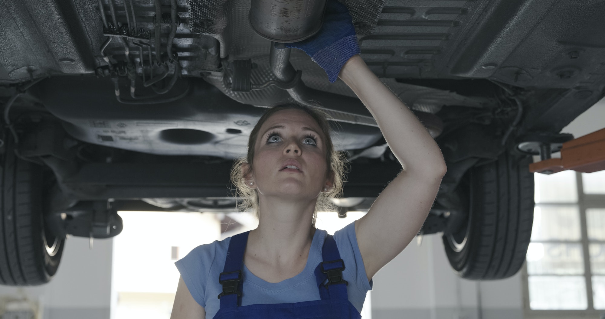 Female mechanic working under a car